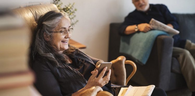 starsza kobieta z telefonem na kanapie, dalej starszy mężczyzna na krześle
