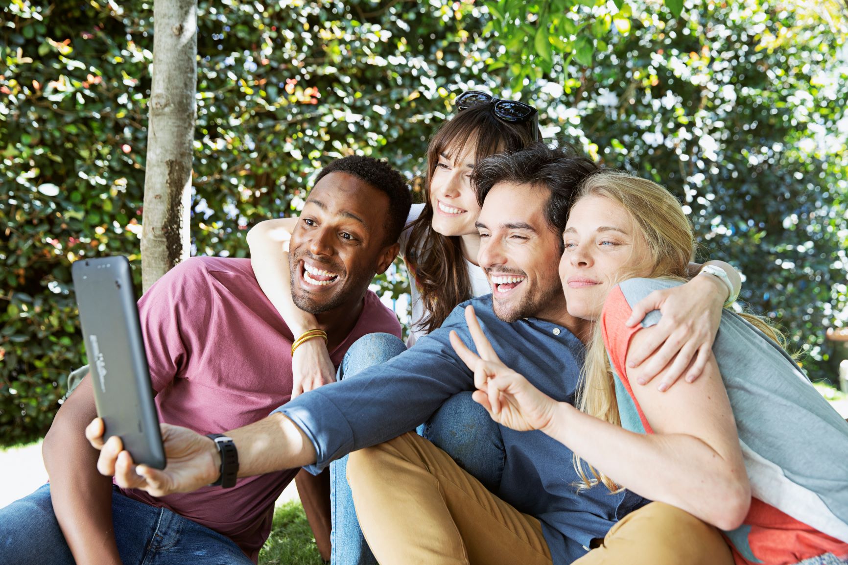 rożni ludzie - kolor skóry, płeć, pochodzenie - robią sobie wspólne zdjęcie telefonem 
